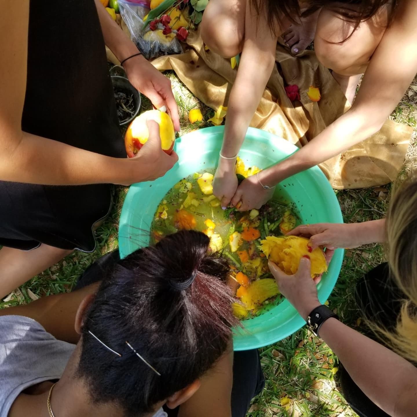 Hands gathered around a bowl of fruit during a community wellness activity